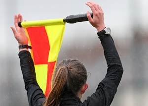 An assistant referee signals with a flag