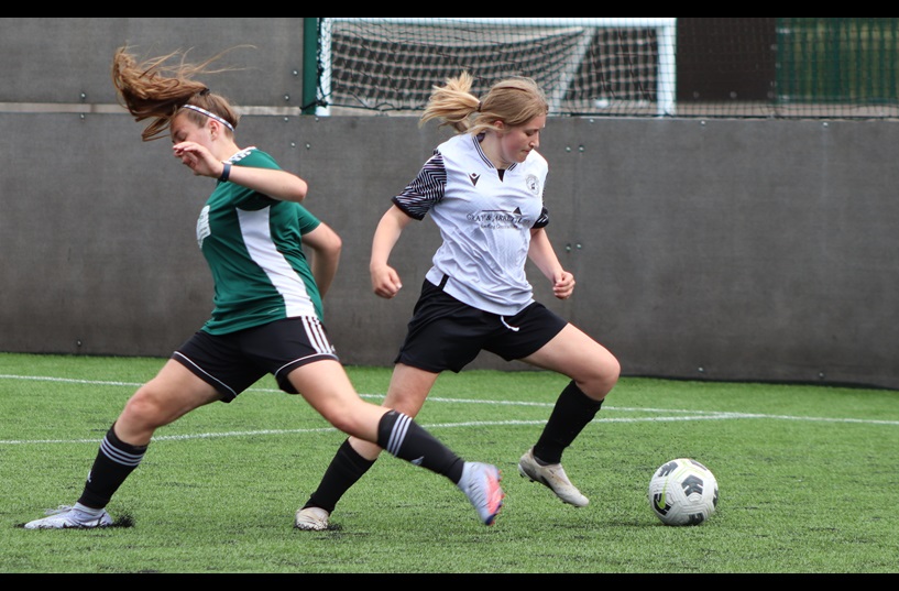 A female player evades a tackle from a defender with a quick turn with the ball
